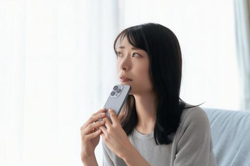 スマホを持って考えごとをする女性 スマホを持って考えごとをする女性 女性,スマホ,スマートフォンの写真素材