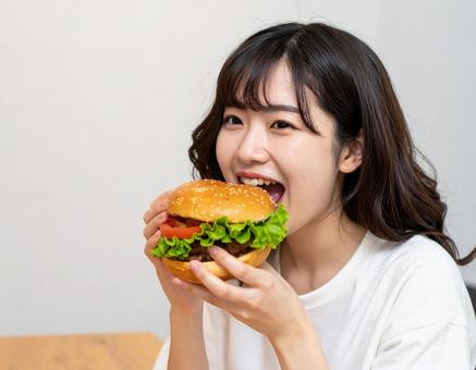 おいしそうにハンバーガーにかじりつく女性 おいしそうにハンバーガーにかじりつく女性の写真