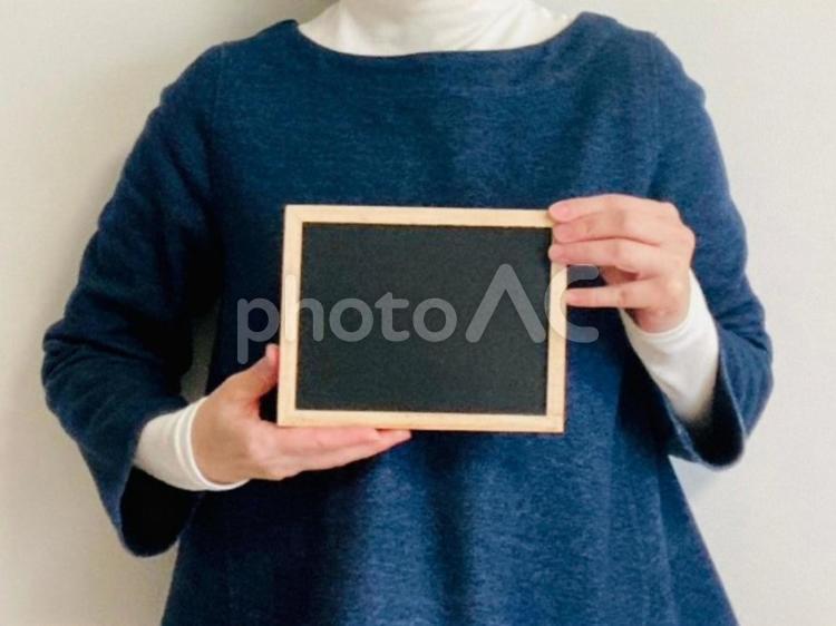 黒板を持つ女性（デニムトップス） 黒板,解説,メッセージの写真素材
