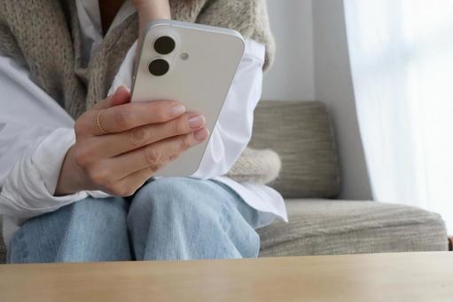 ソファーに座ったスマホを持つ女性 スマホ,女性,ビジネスの写真素材