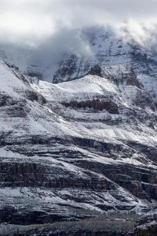 雪の積もった険しい山岳の岩肌_縦 山,ロッキー,雪の写真素材