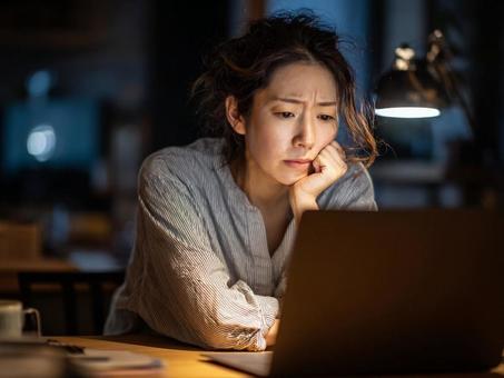 不安げに調べものをする女性 不安げに調べものをする女性の写真