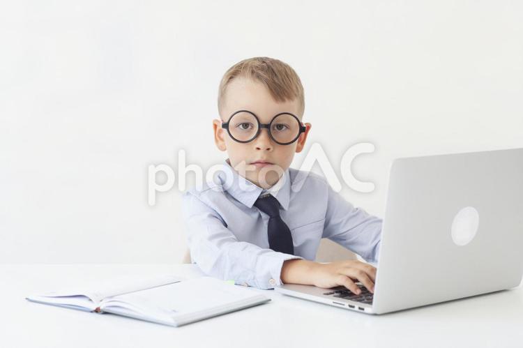 ビジネスマンに扮した男の子がデスクワークをする 子ども,お仕事,職業の写真素材