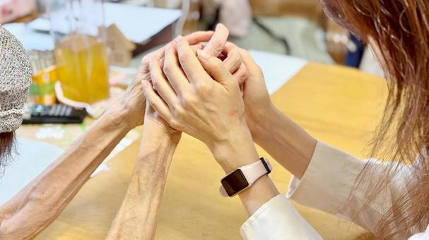 両手で高齢女性の手を握る女性の手 高齢者,介助,介護の写真素材