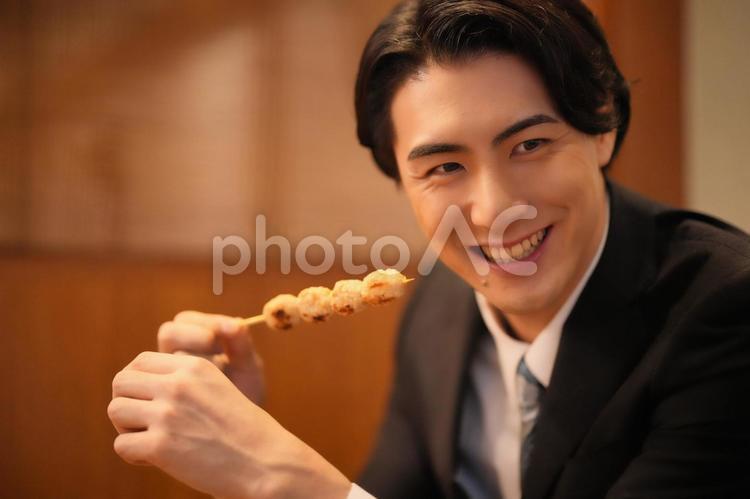 焼き鳥を持って誰かと話す男性 男性,焼き鳥,持つの写真素材