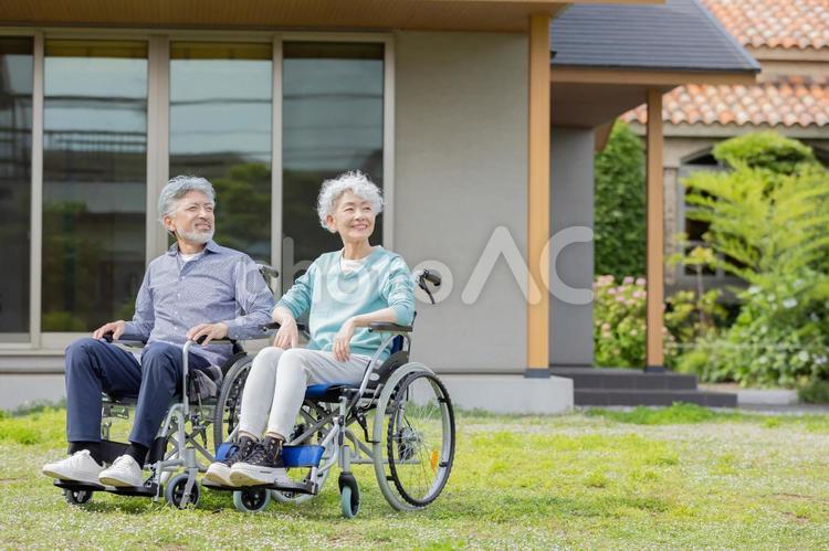 住宅の前で車椅子に乗るシニア夫婦 車椅子,介護,見上げるの写真素材