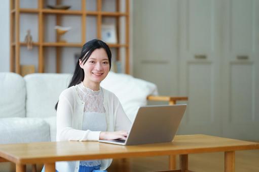 カメラ目線で笑うパソコン作業中の白い服の女性 女性,ノートパソコン,座るの写真素材
