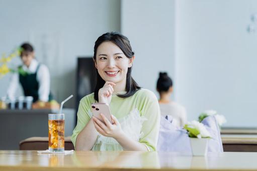 カフェでスマホを使う若い女性 カフェでスマホを使う若い女性 女性,カフェ,笑顔の写真素材