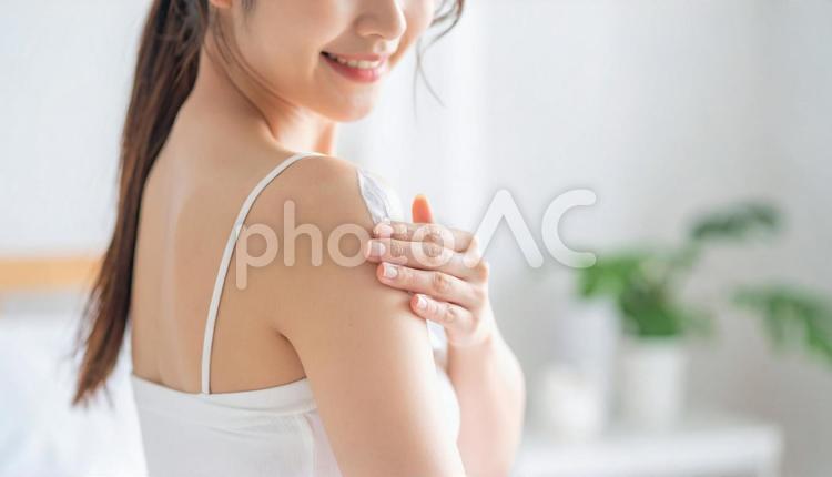 部屋で日焼け止めを塗る女性 スキンケア,女性,日焼け止めの写真素材