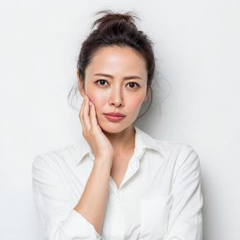 頬に手を当てて悩む若い日本人女性 頬に手を当てて悩む若い日本人女性の写真