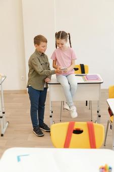 微笑んで携帯を見る生徒たち 男の子,女の子,子どもの写真素材