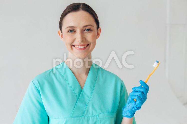 カメラ目線で黄色の歯ブラシを持って笑顔の女性 女性,歯科医,歯ブラシの写真素材
