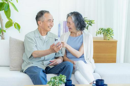 リビングでスマホを見るシニア夫婦 スマホ,シニア,笑顔の写真素材