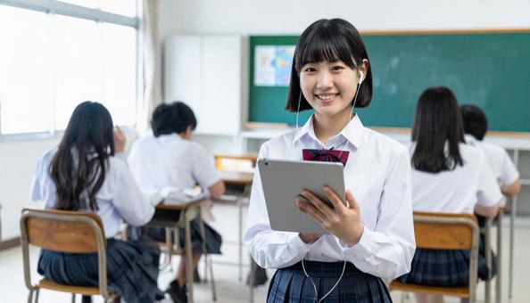 イヤホンをしてタブレットを見る女子学生 イヤホンをしてタブレットを見る女子学生の写真