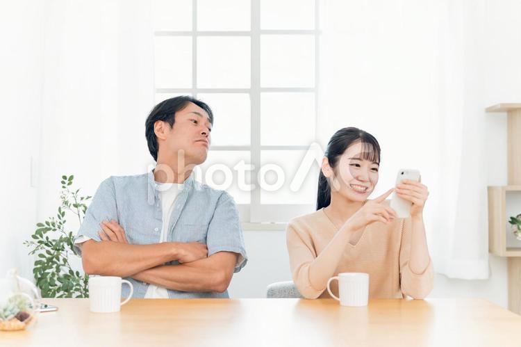 女性のスマホをのぞく男性（怒る） マンネリ,無関心,退屈の写真素材