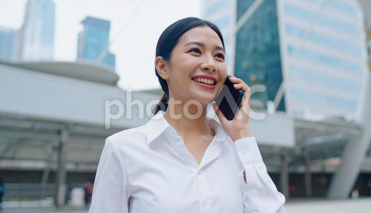 オフィス街でスマホで話すビジネスウーマン キャリアウーマン,エネルギッシュ,キャリアアップの写真素材