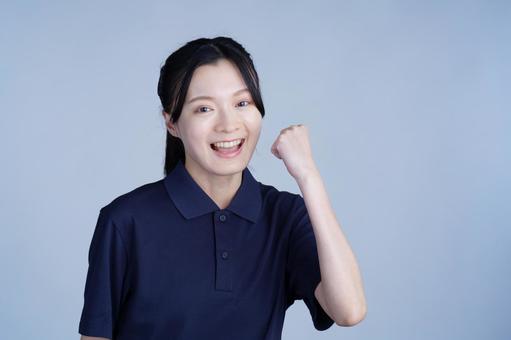紺色の服の女性が笑顔で手を上げる 女性,ガッツポーズ,笑顔の写真素材