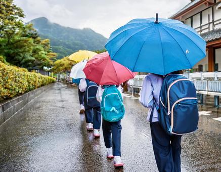 雨の日の小学生の登校風景の写真