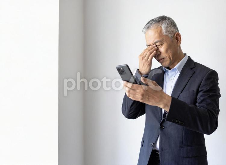 スマホ 60代 笑顔 老眼 ビジネスマン,老眼,スマホの写真素材