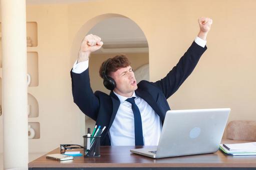 目を瞑りガッツポーズの男性 男性,外国人,ノートパソコンの写真素材