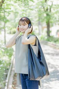 新緑の中ヘッドフォンで音楽を聴く若い女性 新緑の中ヘッドフォンで音楽を聴く若い女性 女性,外出,ヘッドフォンの写真素材