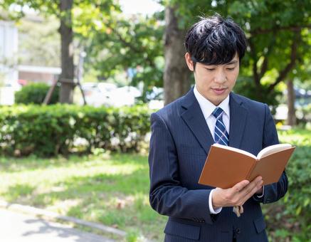 屋外で読書しているサラリーマン 屋外で読書しているサラリーマンの写真