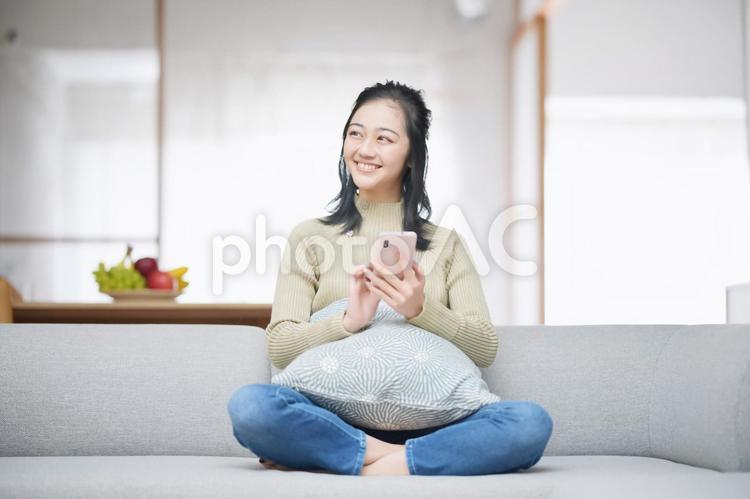 胡坐でスマホを持ち振り向く女性 女性,横を向く,日本人の写真素材