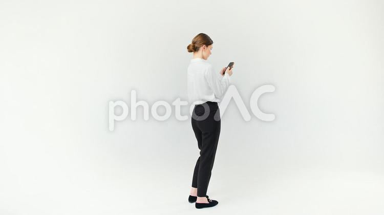 スマホを見ている横向きの外国人女性 女性,スマートフォン,持つの写真素材
