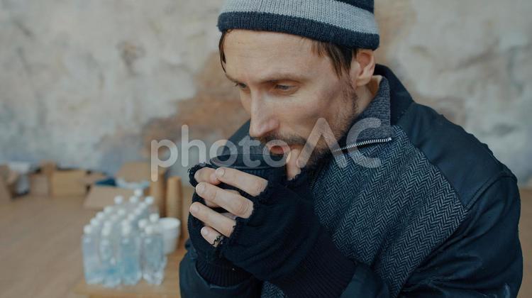 飲み物を持っている男性と後ろにたくさんの水 男性,ニット帽,人物の写真素材