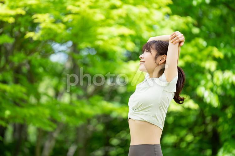 緑の中でストレッチをする笑顔の女性 女性,ストレッチ,運動の写真素材