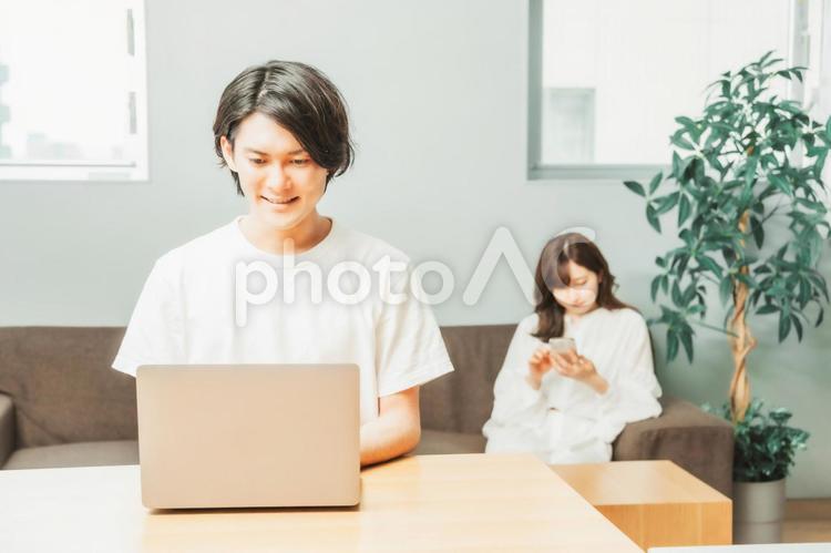 家でテレワークする男女（男性・笑顔） テレワーク,リモートワーク,ノートパソコンの写真素材