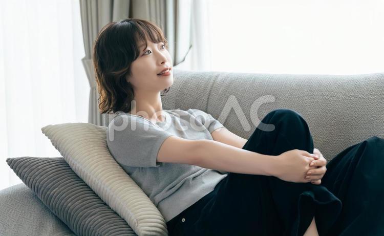 リビングのソファに座る笑顔の女性 女性,ソファ,微笑むの写真素材