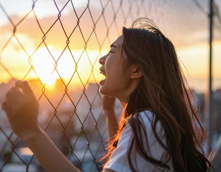 夕日に向かって叫ぶ女性 夕日に向かって叫ぶ女性の写真