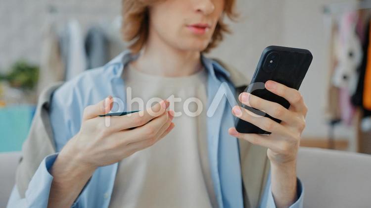 クレジットを見て携帯を見る男性の鼻から下 鼻から下,男性,人物の写真素材