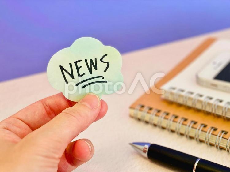 ニュースと書かれたメモを持つ手元 ニュース,お知らせ,案内の写真素材