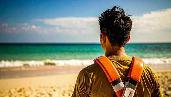砂浜から海を見つめるライフセーバーの男性 砂浜から海を見つめるライフセーバーの男性の写真