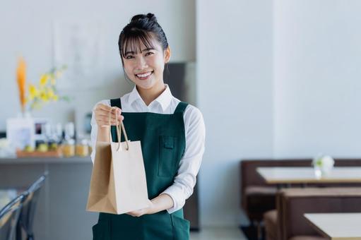 商品を渡す若い女性の店員 商品を渡す若い女性の店員の写真