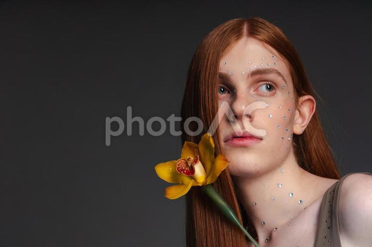 黄色の花と左目が髪で隠れた女性 女性,花,シンビジウムの写真素材