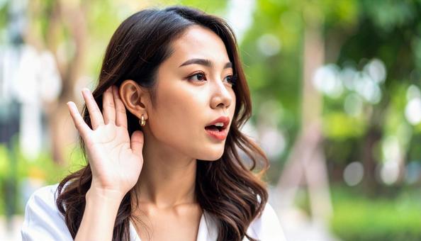 耳に手をあてよく聞くジェスチャーの女性 耳に手をあてよく聞くジェスチャーの女性の写真