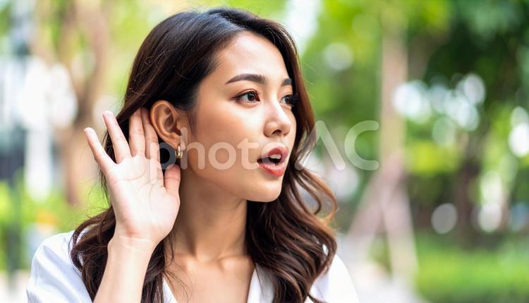 耳に手をあてよく聞くジェスチャーの女性 女性,耳,手の写真素材