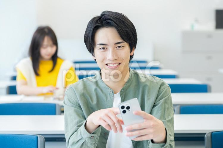 教室でスマホを見る大学生 スマホ,笑顔,大学生の写真素材