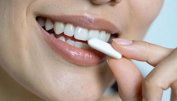 デンタルケアでガムを口にする女性の写真