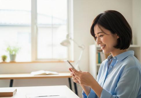 自宅で微笑む女性がスマホを操作している 自宅で微笑む女性がスマホを操作しているの写真