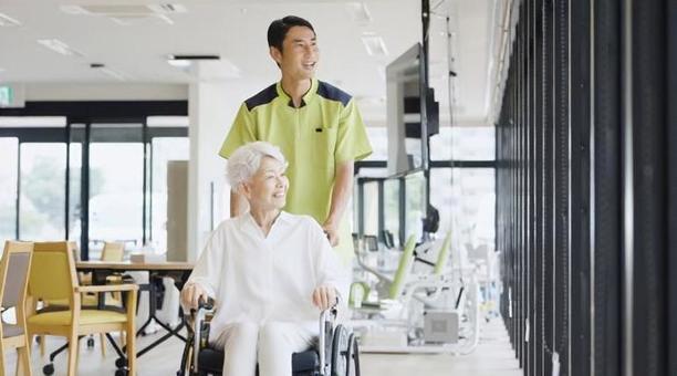 車椅子で散歩をする高齢者と介護士 車椅子で散歩をする高齢者と介護士の写真