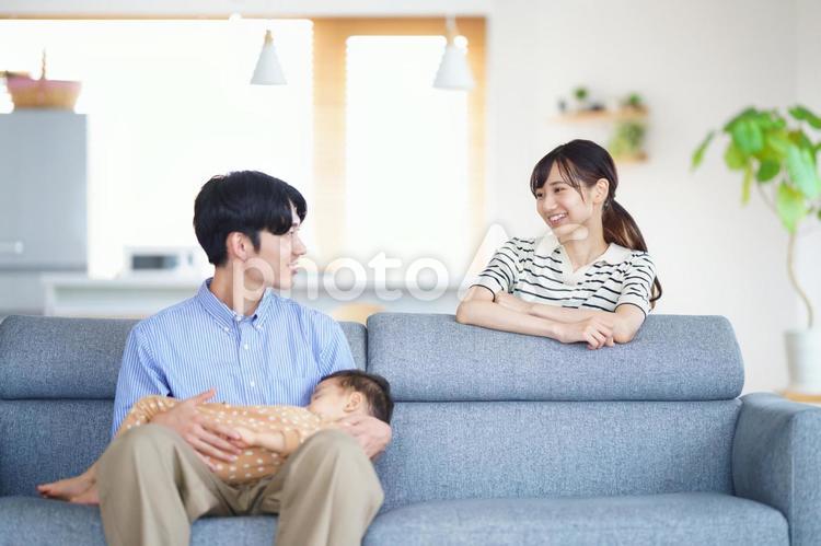 寝ている子供を抱く男性と話す女性 親子,振り向く,寝かしつけの写真素材