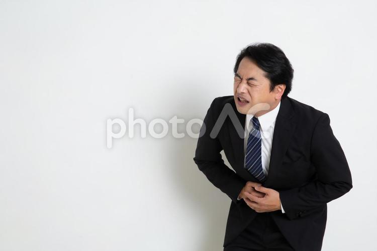 ストレスでお腹が痛くなった中年のサラリーマン男性（コピースペース） 中年,上司,会社員の写真素材