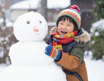 雪だるまを作って喜ぶ子供の冬の屋外風景の写真