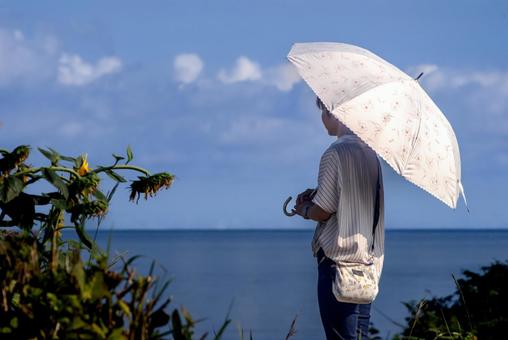 <素材>夏の海と向日葵を眺める日傘の女性 <素材>夏の海と向日葵を眺める日傘の女性 女性,ひまわり,空の写真素材