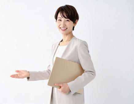 書類を持ち、笑顔で案内する会社員女性 書類を持ち、笑顔で案内する会社員女性の写真