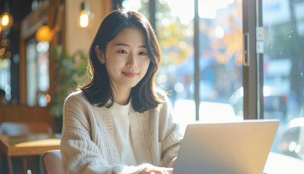 カフェでノートパソコンを使う日本人女性 カフェでノートパソコンを使う日本人女性の写真